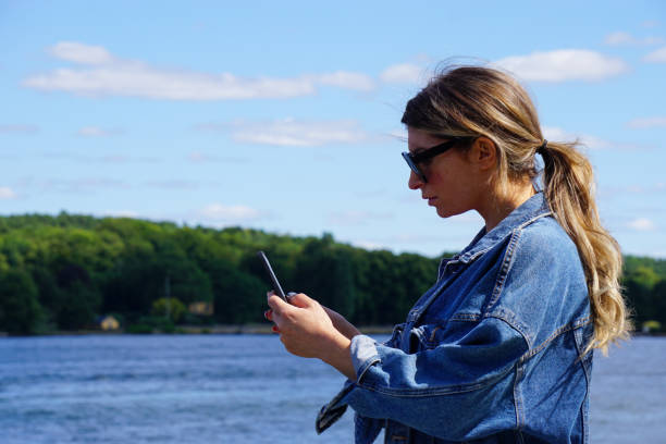 istock Side view of woman using mobile phone while standing by sea 1474397223