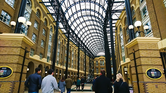 Hay's Galleria, London, United Kingdom - February 18, 2018: people walking into redeveloped warehouse and wharf under a curved glass ceiling