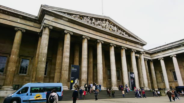 front view of the exterior and facade of the entrance of The British Museum with people entering and leaving the museum The British Museum, London, United Kingdom - May 16, 2018: front view of the exterior and facade of the entrance with people entering and leaving the museum british museum stock pictures, royalty-free photos & images