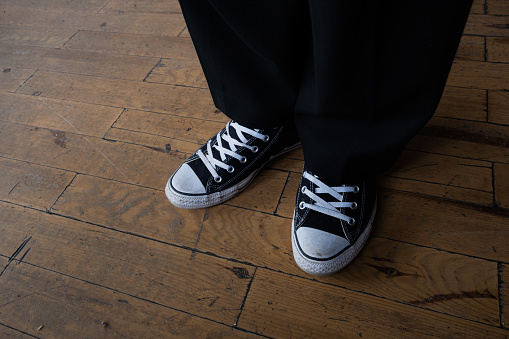 Black canvas sneakers on a wooden floor.