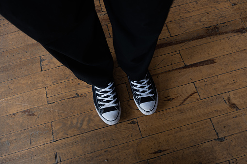 Black canvas sneakers on a wooden floor.