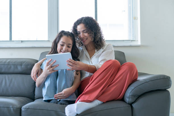 istock Mother and daughter having a good time and using digital tablet on sofa at home 1474400224