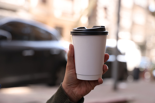 Close up hand holding a white coffee paper cup
