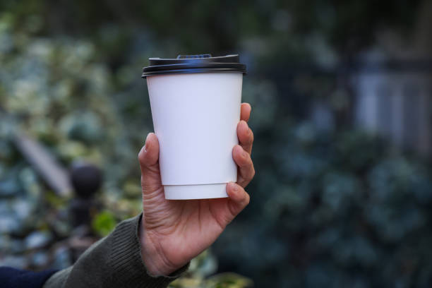 Close up hand holding a white coffee paper cup - fotografia de stock