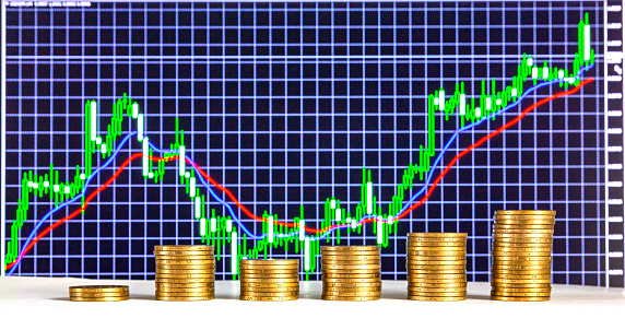 Coins of the Ukrainian hryvnia are stacked against the backdrop of a financial chart.