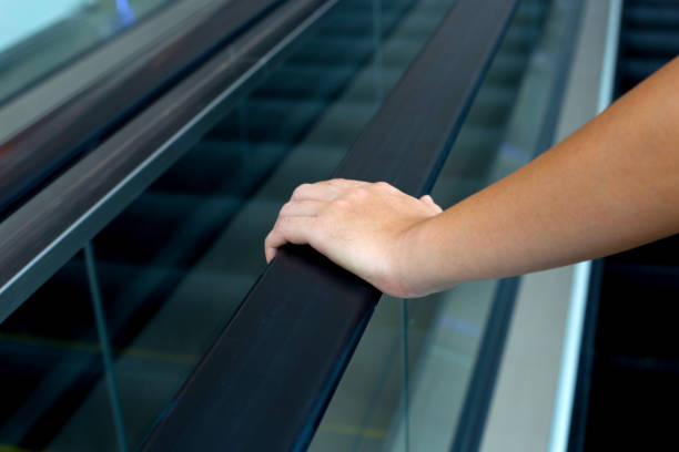 istock Hand holding escalator handrail in shopping mall or building 1474405821