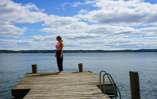 Woman standing on pier over lake against sky