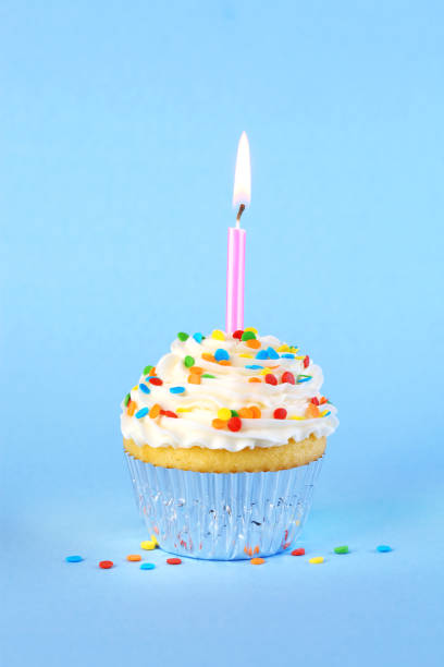 istock Iced birthday cupcake with with lit candle and sprinkles 1474408413