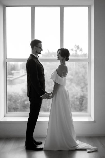 istock groom in a black suit tie and the bride in a bright studio 1474410835
