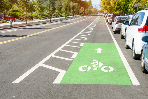 Bicycle lane along a road in a business park. Cars are parked along the lane. Mountain View, CA, USA.