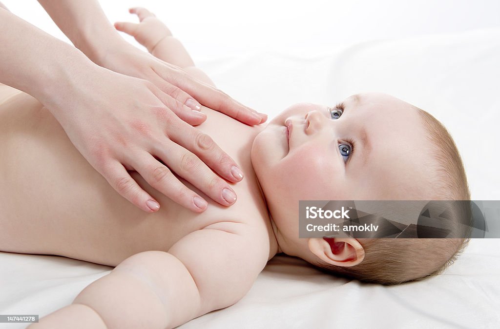 Giving a baby a massage on white linen Mother massaging her lovely baby Activity Stock Photo