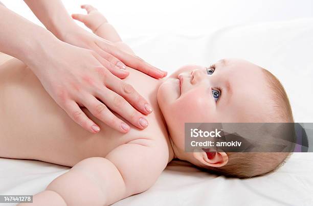 Giving A Baby A Massage On White Linen Stock Photo - Download Image Now - Activity, Affectionate, Baby - Human Age