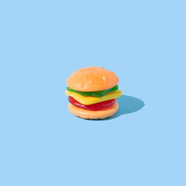istock Hamburger shaped gummy candy with sunlight shadows on blue background. 1474413967