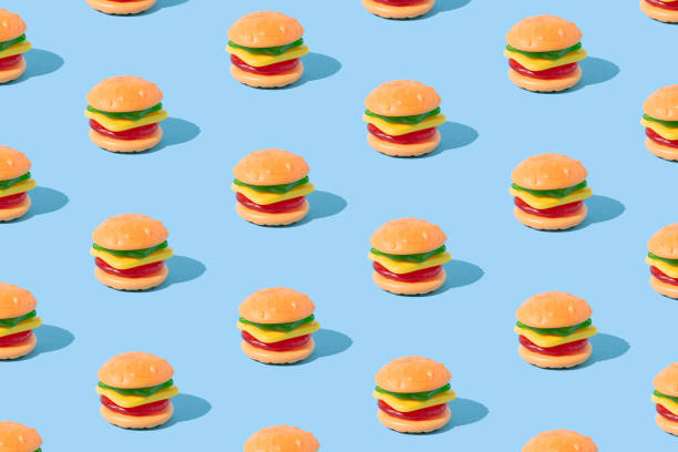 istock Hamburger shaped gummy candy with sunlight shadows on blue background. Summer dessert pattern. 1474413981