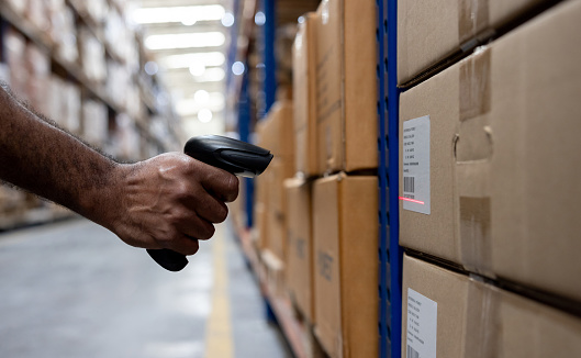 Close-up on a warehouse worker scanning a bar code on a box - distribution warehouse concepts