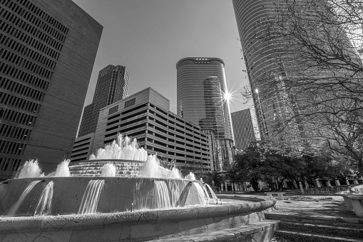 A fountain surrounded by skyscrapers in downtown Houston, TX with afternoon sunburst.