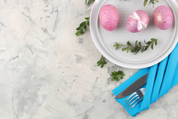 istock Easter. Pink Easter eggs and a knife with a fork and a plate on a light concrete background. Easter table setting. Happy easter. holidays. top view. 1474437436