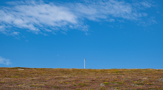 Panoramic nature landscape with electric pylons against blue cloudy sky.