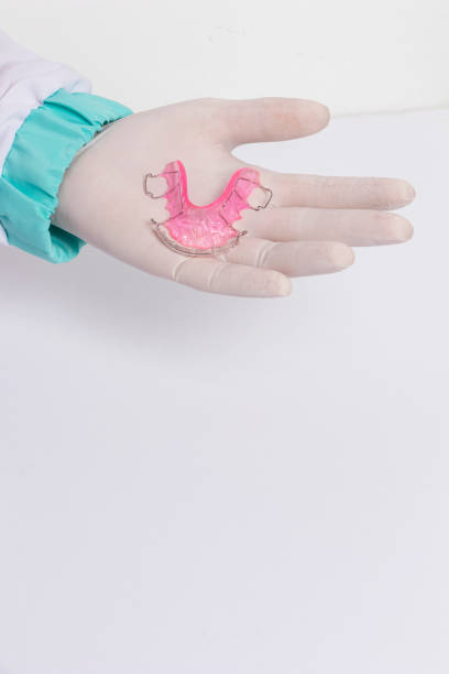 istock Hands in latex gloves with pink retainer 1474443773