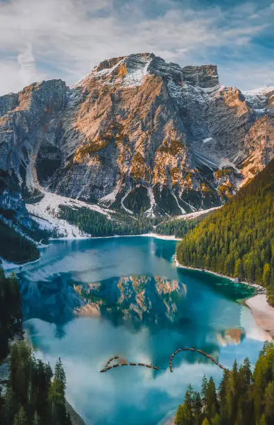 Aerial photo of crystal clear lake of Lago di Braies with beautiful Seekofel mountain reflection and tour boats at early morning time in Pragser Wildsee, Dolomites, South Tyrol, Italia