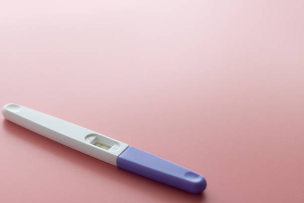 パステルの薄いピンクの背景に白いプラスチック妊娠検査陽性、2本の縞模様の結果。クローズ アップ。 - pregnancy test human pregnancy two objects isolated ストックフォトと画像