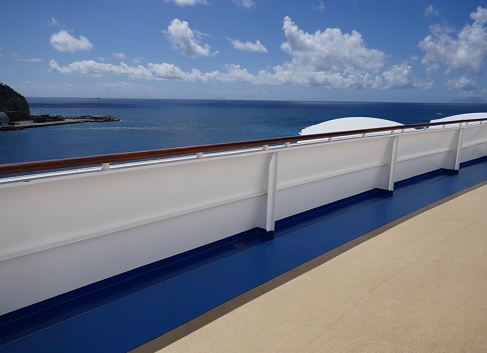 View of a small boat in the ocean from the deck of a cruise ship.