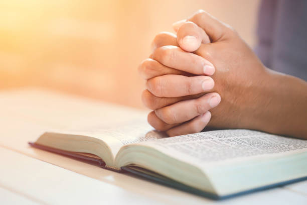 istock Man's Praying Hands Over The Bible with sunlight. 1474464993