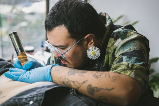 Queer tattoo artist tattooing a client
