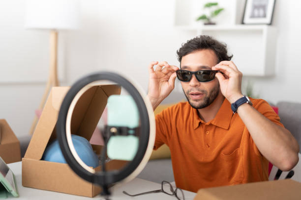 istock Young man, trying on sunglasses while recording a video for social media. 1474467978