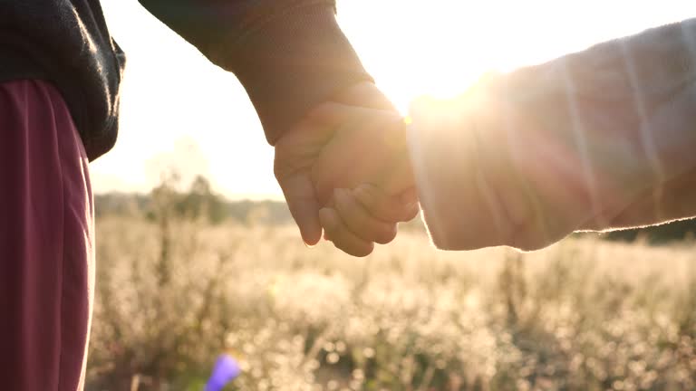 Happy Family Concept. Hands holding, joining of mother and child daughter at sunset on natural background, 4K. Concept of Happy Family, Love, Couple, Parent, Toddler, Valentines Day