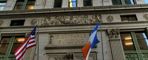 знак справедливого здания, обрамленный флагами в нью-йорке - equitable building стоковые фото и изображения