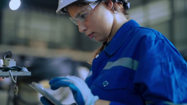 Engineer checking robotic welding arm in manufacturing warehouse