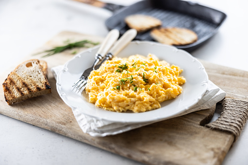 Plate of scrambled organic eggs served with bread toasted on a griddle pan.