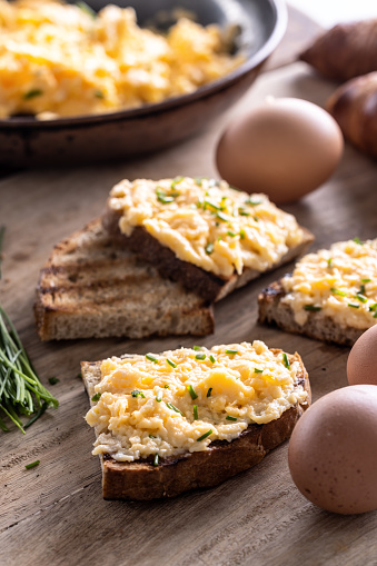 Toasts of bread with generous portion of scrambled eggs on top of it, sprinked with freshly chopped chives.