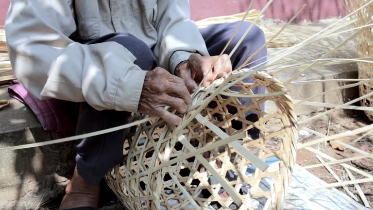 Close-up view of elderly hands weaving folk wisdom baskets