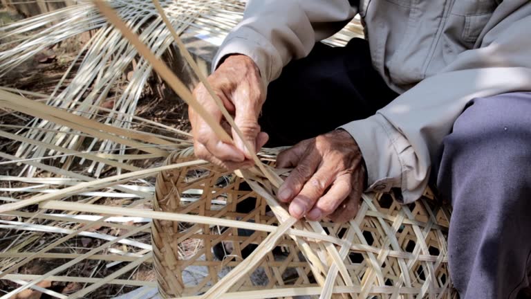 Close-up view of elderly hands weaving folk wisdom baskets