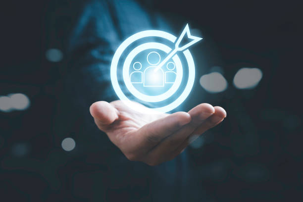 Businessman holding virtual human icon inside of dartboard with arrow for customer target group , Business marketing position concept.