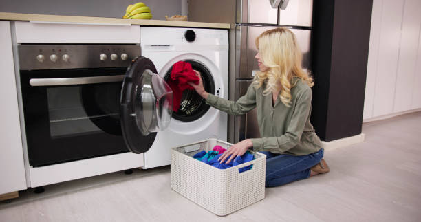 istock Woman Loading Dirty Clothes In Washing Machine For Washing 1474498451