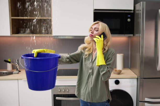 istock Woman Calling Plumber While Collecting Leaking Water 1474498471