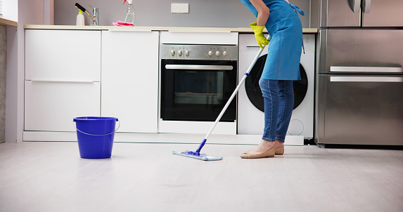 Happy Woman Cleaning Floor With Mop In Kitchen At Home