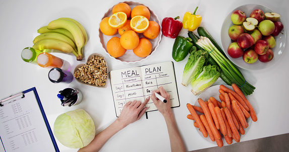 Female Dietitian Doctor Writing Meal Plan In Goals