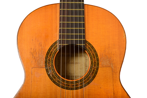 Close-up of old acoustic guitar fretboard with selective focus in the center. Neck perspective with blurred soundhole and strings. Music concept