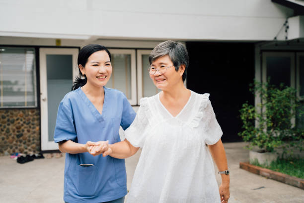 陽気なアジアの介護者と家の外を歩く患者