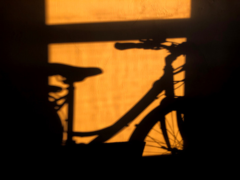 Shadow of a bike against an orange wall