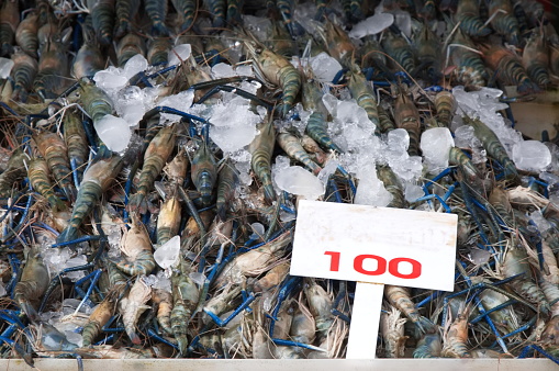 Sea prawns, price tags of 100 baht, arranged in piles waiting for customers to buy This photo was taken at Mae Klong Railway Market, Samut Songkhram Province, Thailand.