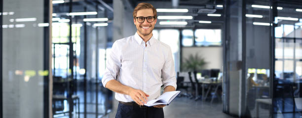 istock Handsome young businessman standing in modern office. 1474506692