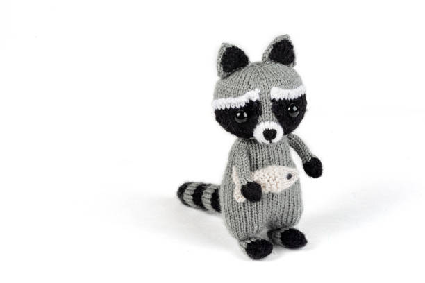 istock knitted raccoon with fish in hands isolated on white backgrounde 1474507041