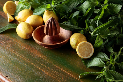 Fresh juicy lemons with mint on the old wooden background.