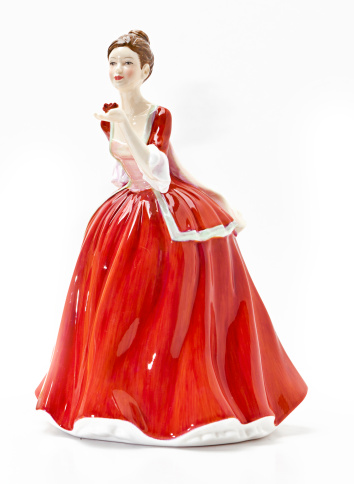 An antique female porcelain figurine wearing a long red dress