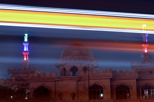 A wide angle long exposure shot in the night in front of Tomb with light trails of moving vehicles at Mukarba chowk flyover, Delhi, India.
